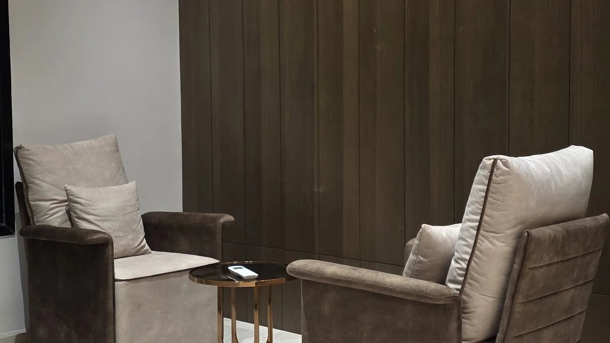 Pair of custom brown and beige velvet armchairs with a rose-gold round side table against a dark wood-panelled wall — Flamingo Lifestyles reading nook detail, Bengaluru villa