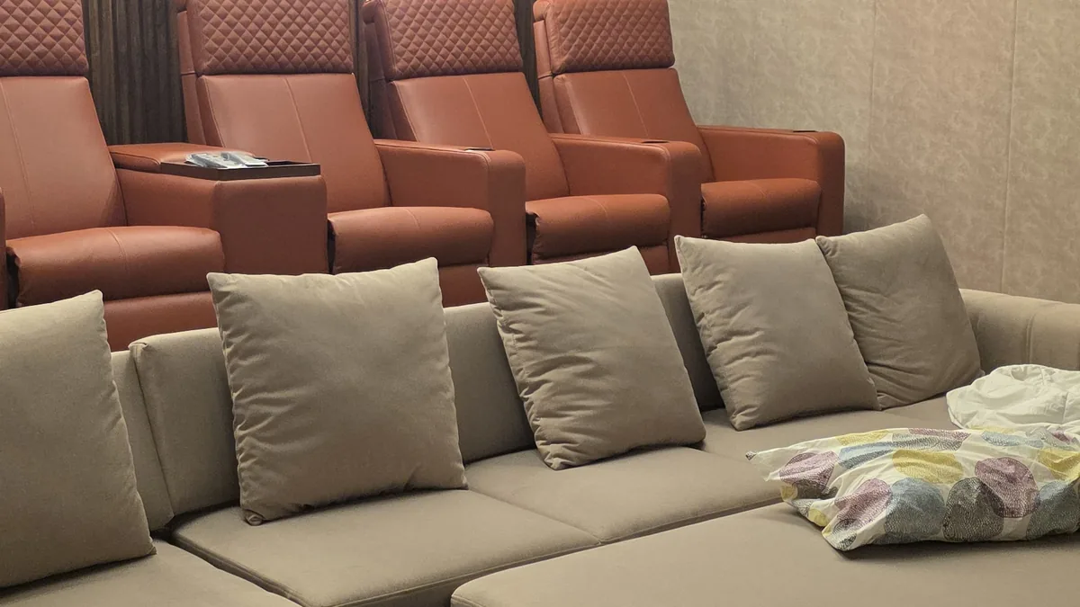 Home theatre with 4 custom tan-leather recliners, projector-mounted ceiling, and a cream modular sofa — a complex multi-piece install requiring site preparation and crew coordination — Flamingo Lifestyles Bengaluru