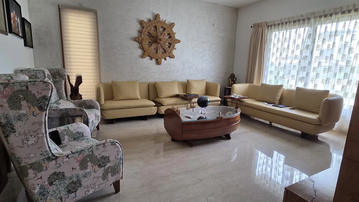 Residential living room with custom mustard velvet sofa set, printed wingback accent chair and a solid-wood boat-shaped coffee table — Flamingo Lifestyles bespoke furniture, Bengaluru