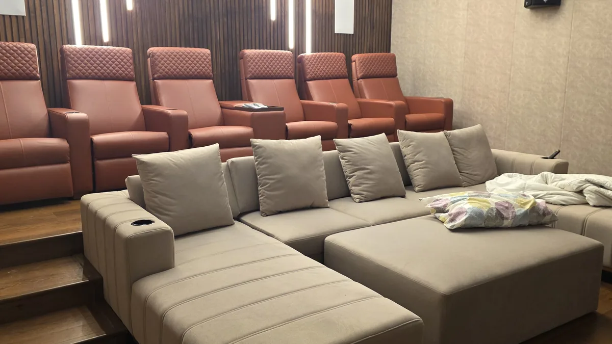 Custom home-theatre recliner row in tan leather with a cream sectional sofa and ottoman platform — Flamingo Lifestyles Bengaluru villa project